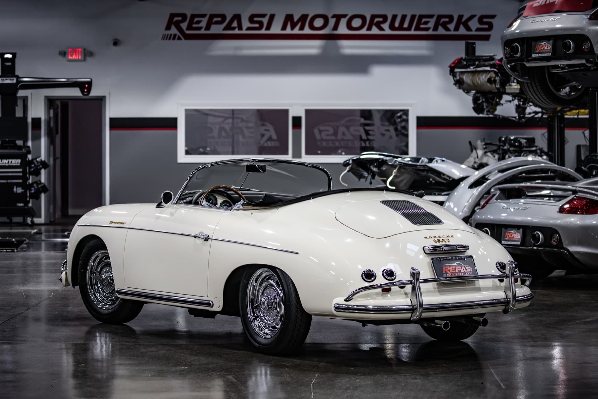 White Porsche 356 Speedster rear three-quarter view with a Carrera GT in the background at Repasi Motorwerks