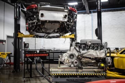 Porsche on lift with engine removed onto cart below during engine-out service