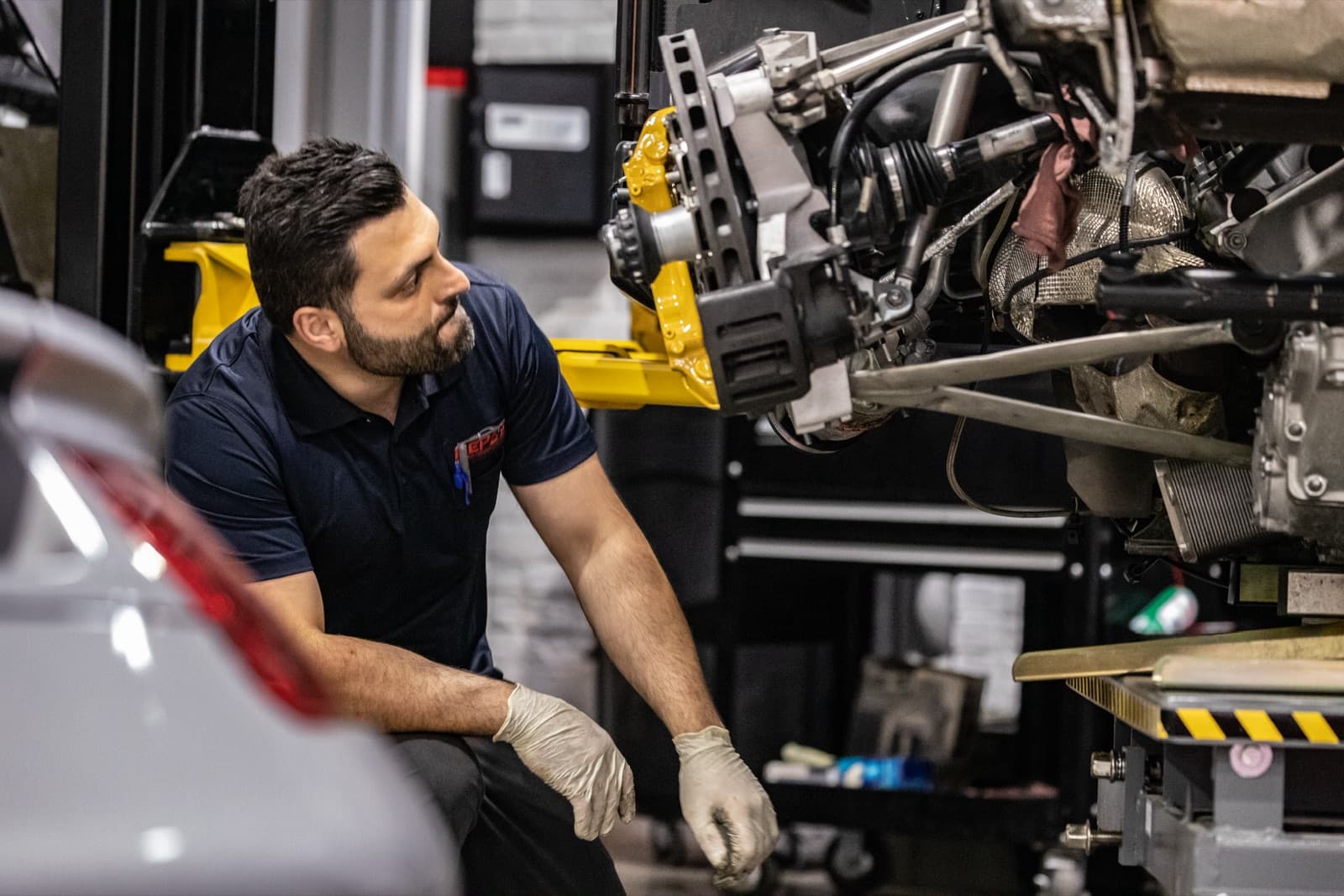 Technician inspecting Porsche suspension components on lift