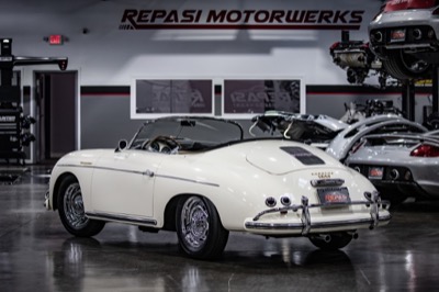 White Porsche 356 Speedster rear three-quarter view with a Carrera GT in the background